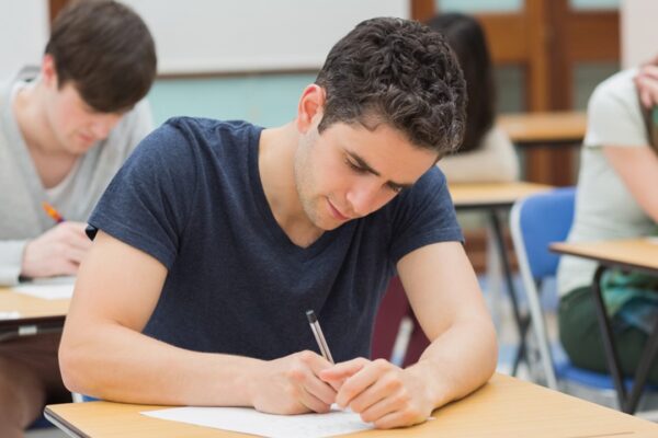 Estudante concentrado realizando a prova do vestibular Fuvest. A imagem retrata a seriedade e a dedicação exigidas durante o exame, que é um dos principais processos seletivos para ingresso na Universidade de São Paulo (USP).