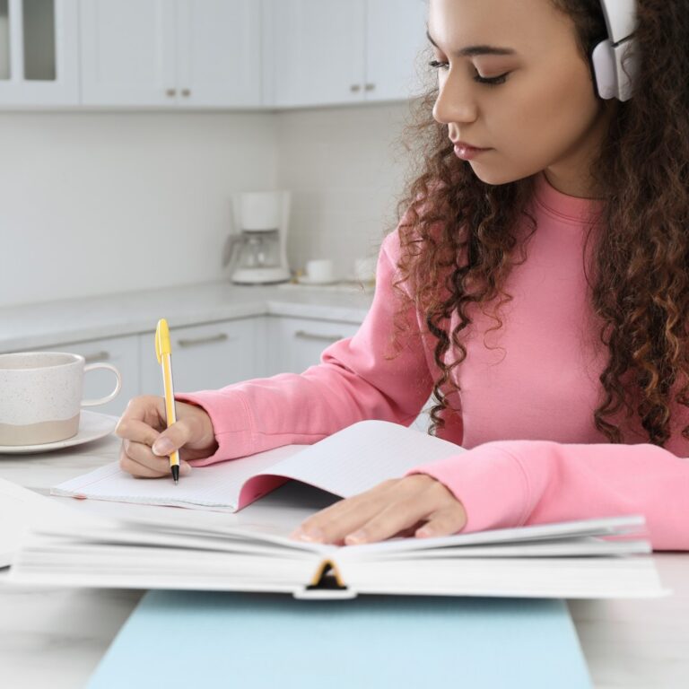 Estudante fazendo anotações enquanto estuda com uma lista de exercícios para se preparar para o ENEM.
