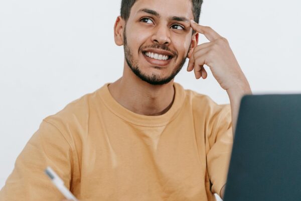 Estudante sorridente fazendo anotações e usando um laptop, representando a pesquisa sobre como funciona o SiSu, o Sistema de Seleção Unificada para ingresso em universidades públicas.