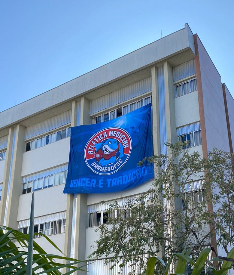 Fachada do prédio de medicina da UFSC, localizada em Florianópolis, com uma bandeira da atlética do curso.