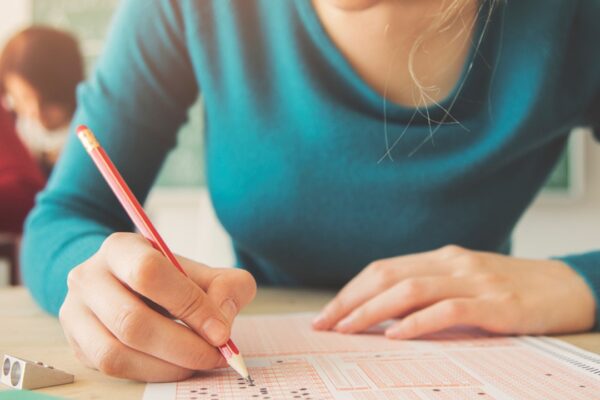 Estudante preenchendo cartão-resposta em prova de múltipla escolha, ilustrando como funciona o Enem, o exame mais importante para ingresso em universidades no Brasil.