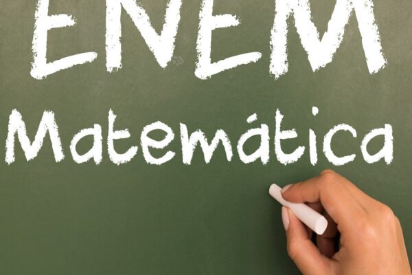 Quadro verde com a inscrição 'ENEM Matemática' destacando tópicos sobre o que mais cai em matemática no Enem, com uma mão segurando giz.
