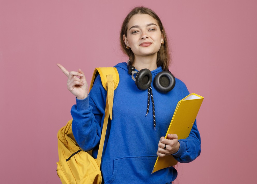 Estudante com mochila, caderno e fones de ouvido, preparada para estudar para o Enem.