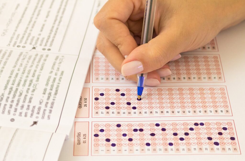 Mão preenchendo cartão-resposta da prova do Enem, representando preparação para o conferir o resultado do Sisu 2025.