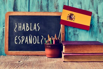 Quadro com a frase "¿Hablas Español?", bandeira da Espanha, lápis coloridos e livros, representando o estudo de Espanhol no Enem.