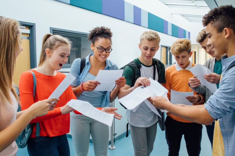 Grupo de estudantes animados conferindo seus resultados após estudar por questões, método que pode te levar à aprovação no Enem e vestibulares, ajudando na preparação eficiente e no domínio dos conteúdos mais cobrados nas provas.