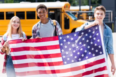 Estudantes americanos segurando a bandeira dos EUA representando a melhor escola dos estados unidos.