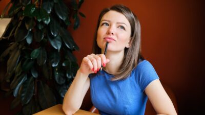 Estudante refletindo sobre os melhores métodos de estudo enquanto escreve em um caderno.
