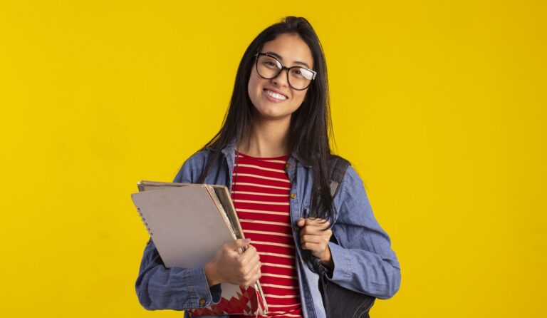 Estudante segurando apostilas e uma mochila em referencia à prática de simulado de vestibulares para a preparação.