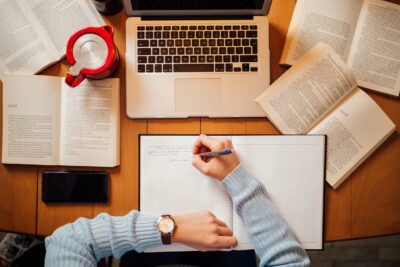 Pessoa estudando com livros abertos, caderno e notebook sobre a mesa, representando o que estudar para o vestibular de forma organizada e eficiente.