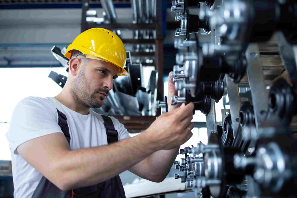 Engenheiro ajustando peças mecânicas em fábrica, ilustrando atividades práticas relacionadas ao que se estuda na faculdade de engenharia mecânica.