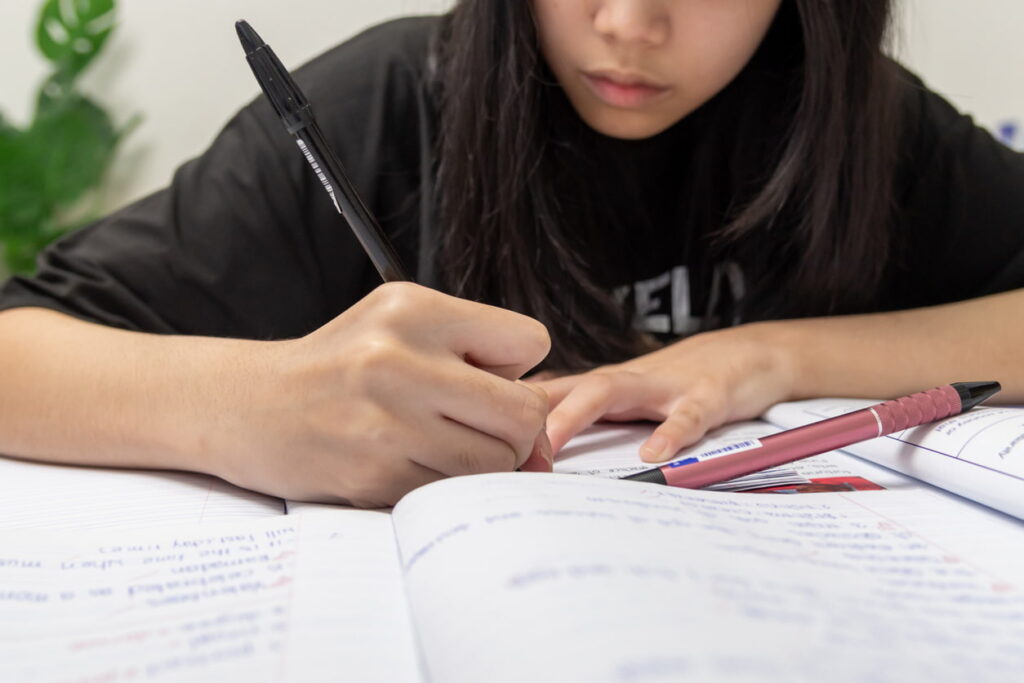 Estudante escrevendo em caderno com foco, representando o início do processo de produção de texto, ideal para conteúdo sobre como fazer uma redação do zero.