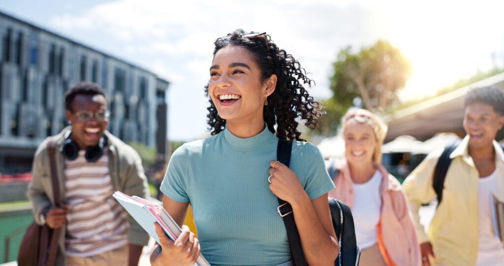 Grupo de estudantes sorrindo e caminhando ao ar livre felizes com o Simulado Preparadão Enem, mostrando entusiasmo e preparação para o exame.