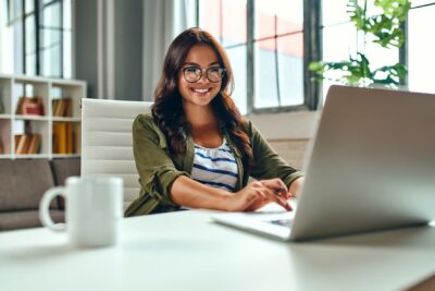 Estudante sorridente usando notebook para participar do Dia 2 do Simulado gratuito, aproveitando os recursos online de preparação para o Enem.