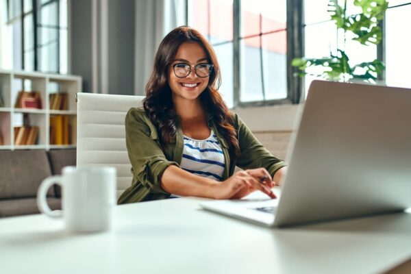 Estudante sorridente usando notebook para participar do Dia 2 do Simulado gratuito, aproveitando os recursos online de preparação para o Enem.