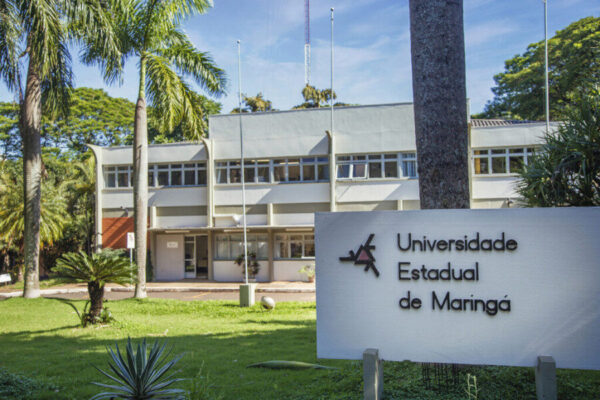 Fachada da Universidade Estadual de Maringá com placa institucional, destacando o Vestibular UEM como porta de entrada para cursos de graduação.