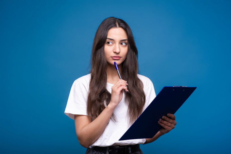 Jovem segurando prancheta e caneta enquanto pensa, ilustrando a dúvida gramatical sobre “sede ou cede”.