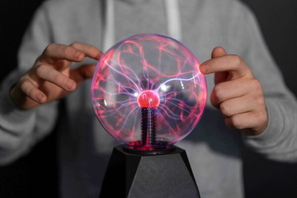 Eletromagnetismo representado por uma pessoa interagindo com uma esfera de plasma, ilustrando os fenômenos de eletricidade e magnetismo.