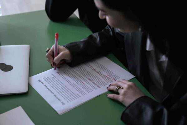 Estudante analisando e destacando uma redação com caneta vermelha, ilustrando como interpretar o tema da redação do Enem sem fugir da proposta.