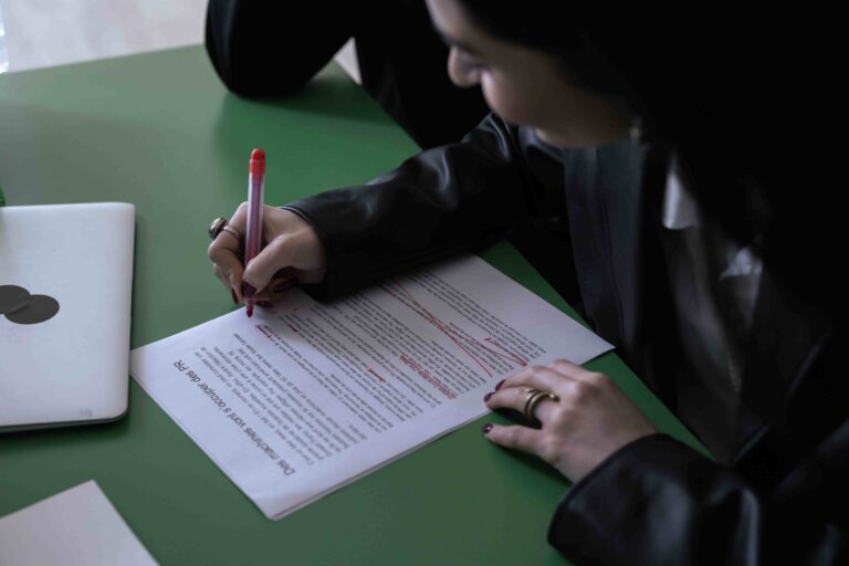 Estudante analisando e destacando uma redação com caneta vermelha, ilustrando como interpretar o tema da redação do Enem sem fugir da proposta.