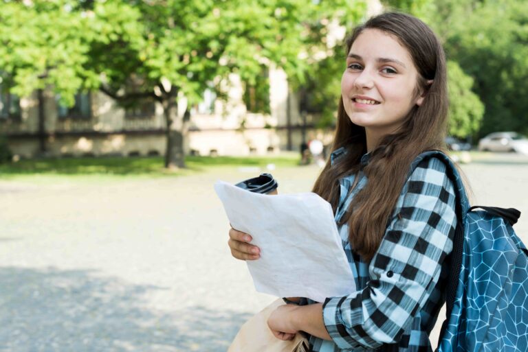 Estudante com mochila e folhas de estudo em ambiente externo, representando a preparação para a primeira fase do vestibular Unicamp 2027.