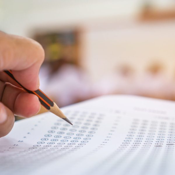 Mão preenchendo cartão de respostas em simulado, representando o Boletim de Desempenho Enem como ferramenta essencial para avaliar a performance do estudante.