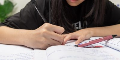 Estudante escrevendo em caderno com foco, representando o início do processo de produção de texto, ideal para conteúdo sobre como fazer uma redação do zero.