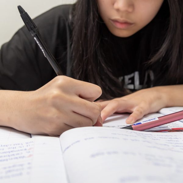 Estudante escrevendo em caderno com foco, representando o início do processo de produção de texto, ideal para conteúdo sobre como fazer uma redação do zero.