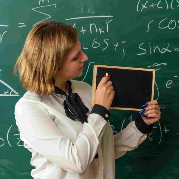 Professora explicando o Teorema de Pitágoras em sala de aula, com fórmulas matemáticas e triângulo retângulo no quadro.