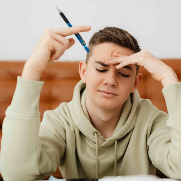 Adolescente com expressão de dúvida estudando em casa, segurando um lápis e refletindo sobre gramática, ilustrando o tema “emcima ou em cima como escrever” de forma prática e educativa.