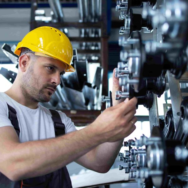 Engenheiro ajustando peças mecânicas em fábrica, ilustrando atividades práticas relacionadas ao que se estuda na faculdade de engenharia mecânica.