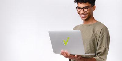 Estudante sorridente segurando notebook com logo da Estuda.com, representando como estudar online por meio de uma plataforma de estudos gratuita.