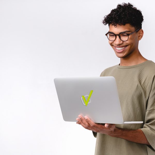 Estudante sorridente segurando notebook com logo da Estuda.com, representando como estudar online por meio de uma plataforma de estudos gratuita.