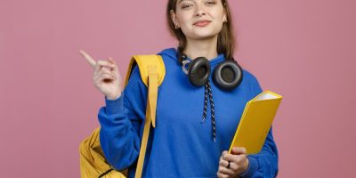 Estudante com mochila, caderno e fones de ouvido, preparada para estudar para o Enem.