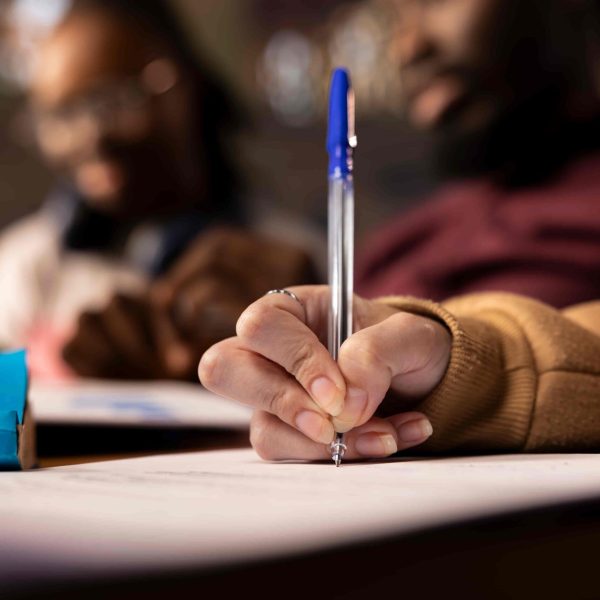 Estudante escrevendo em uma folha durante a preparação para o vestibular, representando o fim das inscrições Fuvest 2027.