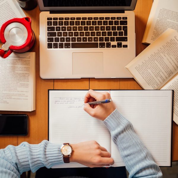 Pessoa estudando com livros abertos, caderno e notebook sobre a mesa, representando o que estudar para o vestibular de forma organizada e eficiente.