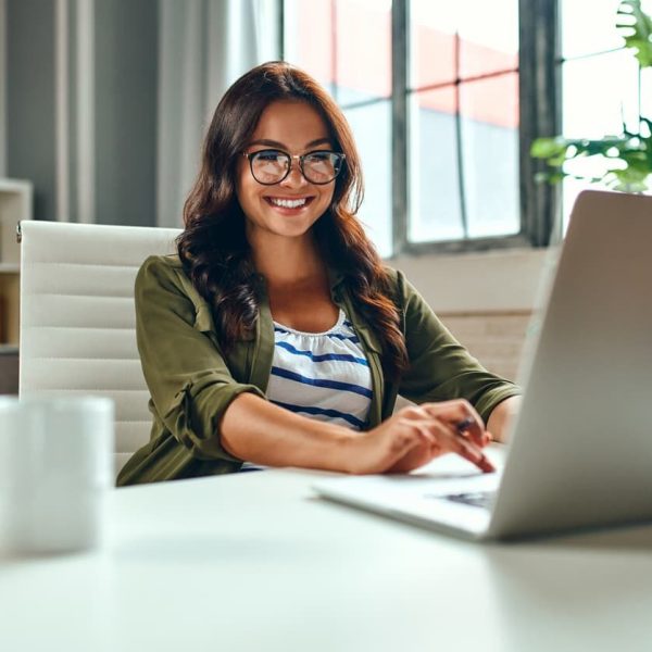 Estudante sorridente usando notebook para participar do Dia 2 do Simulado gratuito, aproveitando os recursos online de preparação para o Enem.