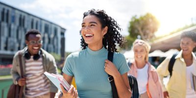 Grupo de estudantes sorrindo e caminhando ao ar livre felizes com o Simulado Preparadão Enem, mostrando entusiasmo e preparação para o exame.
