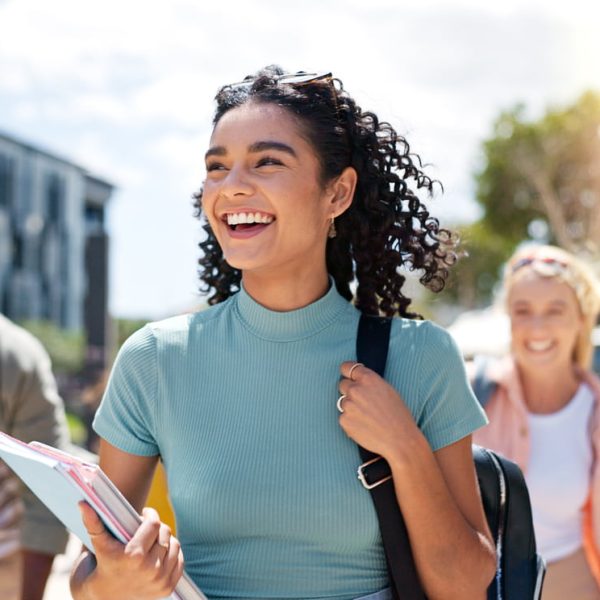Grupo de estudantes sorrindo e caminhando ao ar livre felizes com o Simulado Preparadão Enem, mostrando entusiasmo e preparação para o exame.