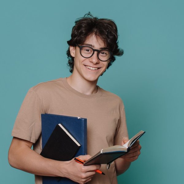 Jovem estudante sorridente segurando cadernos e caneta, representando um treineiro Enem se preparando para a prova.